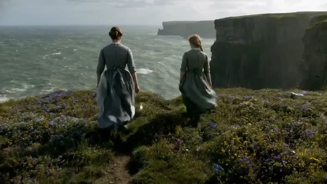 Two women walk towards the cliff by the seaside